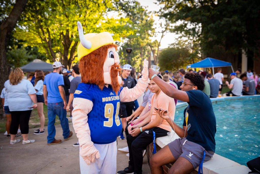 NEO mascot high fives a student
